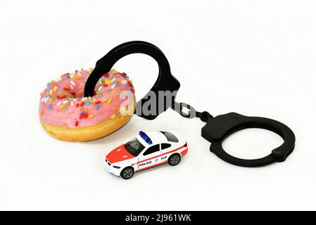 Donut mit Handschellen und Polizeiauto Stockfoto