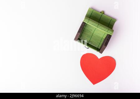 Leere offene grüne kleine Weidenbrust, Behälter auf einem weichen rosa Hintergrund mit einem roten Papierherz. Truhe für Geheimnisse, Schatz. Designelement. Stockfoto