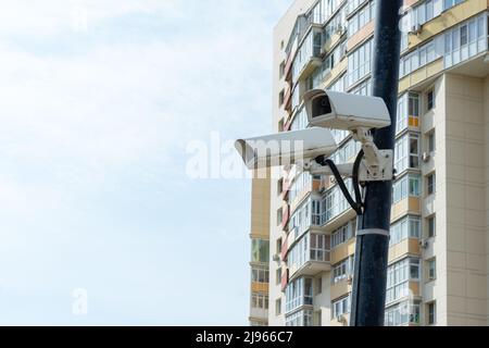 Überwachungskameras auf einem Laternenpfahl in der Nähe eines mehrstöckigen Gebäudes installiert. Sicherheits-cctv-Kamera. Sicherheit in der Stadt. Versteckte Dreharbeiten von dem, was zufällig ist Stockfoto