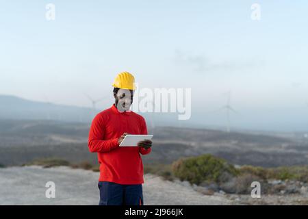 Afrikanischer Ingenieur, der mit Tablet auf der Baustelle arbeitet - Technologie- und Industriekonzept Stockfoto