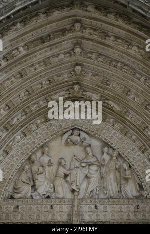 Spanien, Kastilien-La Mancha, Toledo. Kathedrale der Heiligen Maria. Erbaut im gotischen Stil zwischen 1227 und 1493. Hauptfassade. Tor der Vergebung. Erbaut unter der Leitung des Architekten Alvar Martínez (tätig zwischen 1418 und 1440). Tympanon. Skulpturales Relief, das die Jungfrau darstellt, die den heiligen Ildephonsus (607-667) mit dem Chasuble überführt. Stockfoto