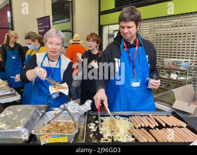 Sydney, Australien. 21.. Mai 2022. Wahlhelfer braten Würstchen vor einem Wahllokal an der International Grammar School in der Kelly Street in Sydney, Australien. Demokratiewürste sind eine Besonderheit der australischen Wahlen. Traditionell gibt es vor vielen Wahllokalen einen Grill, wo die Wähler eine Art Hotdog essen können (Knockwurst in einem weichen Brötchen mit Senf und Ketchup). Mittlerweile gibt es auch vegetarische Alternativen und steht mit Kaffee und Kuchen. Quelle: Carola Frentzen/dpa/Alamy Live News Stockfoto