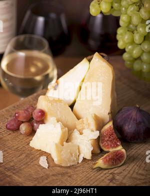 Käseplatte serviert mit Trauben, Melone, Feigen, Cracker, Honig, Nüsse und Weißwein auf einem Holztisch Stockfoto
