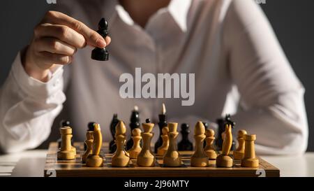 Gesichtslose kaukasische Frau im weißen Hemd, die Schach spielt. Stockfoto