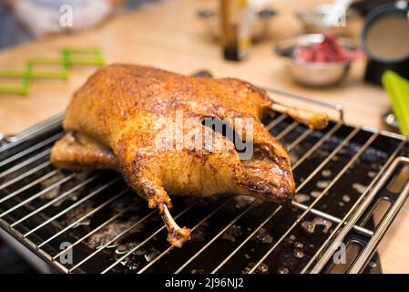 Gebackene Ente auf einem Gestell und Blech aus dem Ofen. Die gekochte Ente kühlt ab. Geröstet auf eine knackige Haut. Stockfoto