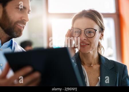 Nahaufnahme der Optometristin, die der Frau hilft, im optischen Laden eine Brille auszuwählen, die ihrem Spiegel zeigt Stockfoto