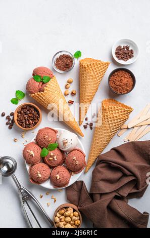 Eiscreme, Waffelbecher und Zusatzstoffe auf hellem Hintergrund. Stockfoto