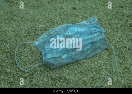 Budva, Gemeinde Budva, Montenegro, Europa. 31.. Juli 2020. Nahaufnahme, weggeworfene gebrauchte medizinische Gesichtsmaske liegt unter Wasser auf dem sandigen Boden. Budva, Montenegro (Kreditbild: © Andrey Nekrasov/ZUMA Press Wire) Stockfoto