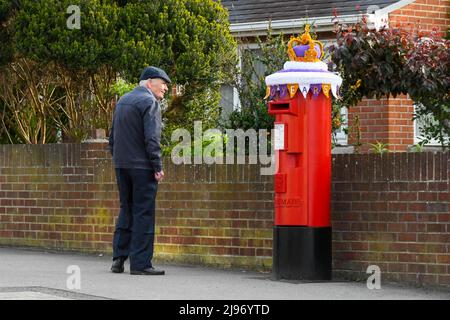 Weymouth, Dorset, Großbritannien. 21. Mai 2022. Ein Bewohner hält an, um sich eine Briefbox in Weymouth in Dorset anzusehen, die zur Feier des Platin-Jubiläums der Königin mit einer gehäkelten Staatskrone geschmückt wurde. Das Platin-Jubiläum von Elisabeth II. Wird vom 2. Juni bis 5. Juni 2022 im Vereinigten Königreich und im Commonwealth zum 70.. Jahrestag des Beitritts von Königin Elizabeth II. Am 6. Februar 1952 gefeiert. Bildnachweis: Graham Hunt/Alamy Live News Stockfoto