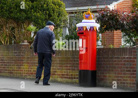 Weymouth, Dorset, Großbritannien. 21. Mai 2022. Ein Bewohner hält an, um sich eine Briefbox in Weymouth in Dorset anzusehen, die zur Feier des Platin-Jubiläums der Königin mit einer gehäkelten Staatskrone geschmückt wurde. Das Platin-Jubiläum von Elisabeth II. Wird vom 2. Juni bis 5. Juni 2022 im Vereinigten Königreich und im Commonwealth zum 70.. Jahrestag des Beitritts von Königin Elizabeth II. Am 6. Februar 1952 gefeiert. Bildnachweis: Graham Hunt/Alamy Live News Stockfoto