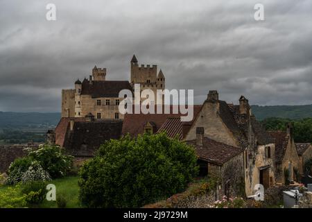 Beynac-et-Cazenac, Frankreich - 12. Mai 2022: Blick auf das Schloss Beynac im Dordogne-Tal unter einem wolkenbedeckten, ausdrucksstarken Himmel Stockfoto