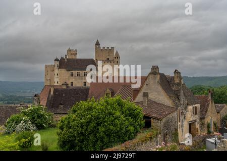 Beynac-et-Cazenac, Frankreich - 12. Mai 2022: Blick auf das Schloss Beynac im Dordogne-Tal unter einem wolkenbedeckten, ausdrucksstarken Himmel Stockfoto