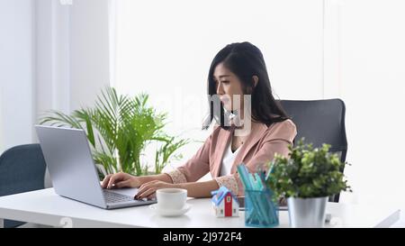 Konzentrierte junge Unternehmerin, die ihre E-Mails auf ihrem Laptop überprüft. Stockfoto