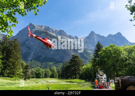 Maienfeld, Schweiz - 20. Mai 2022: Hubschrauber bereitet sich auf den Transport einer Ladung Zement von einem Zement-LKW zu einem entfernten Berg in den Schweizer Alpen vor Stockfoto