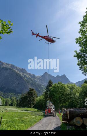 Maienfeld, Schweiz - 20. Mai 2022: Bauarbeiter verladen Ladung und Zementeimer zu einem Hubschrauber für einen alpinen Transport in den Schweizer Alpen Stockfoto