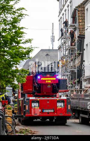 Lippstadt, Deutschland. 21.. Mai 2022. Die Arbeiter entfernen beschädigte Schindeln aus einem Fachwerkhaus in der Innenstadt vor einem Feuerwehrfahrzeug. Einen Tag nach dem Tornado haben die Sanierungsarbeiten im Stadtzentrum begonnen. Kredit: David Inderlied/dpa/Alamy Live Nachrichten Stockfoto