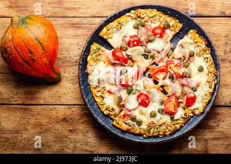 Pizza mit Salami, Käse, Tomate auf einem Kürbis-Fladenbrot. Herbstrezept Stockfoto