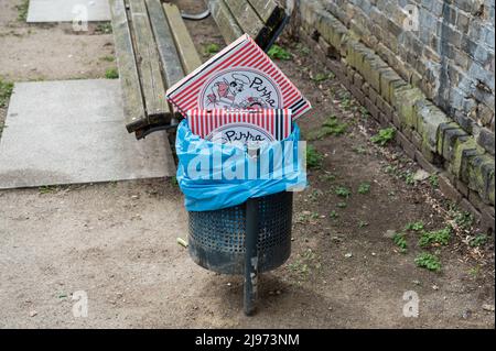 14.04.2022, Berlin, Deutschland, Europa - leere Pizzakartons in einen vollen Mülleimer gequetscht. Stockfoto