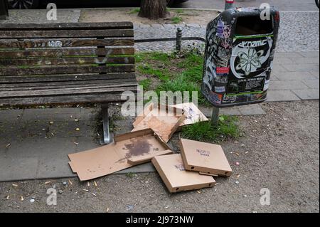 30.04.2022, Berlin, Deutschland, Europa - leere und ausrangierte Pizzakartons liegen auf dem Boden neben einem Mülleimer im Ortsteil Friedrichshain. Stockfoto