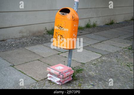 07.05.2022, Berlin, Deutschland, Europa - leere und ausrangierte Pizzakartons liegen auf dem Boden neben einem Mülleimer im Bezirk Mitte. Stockfoto