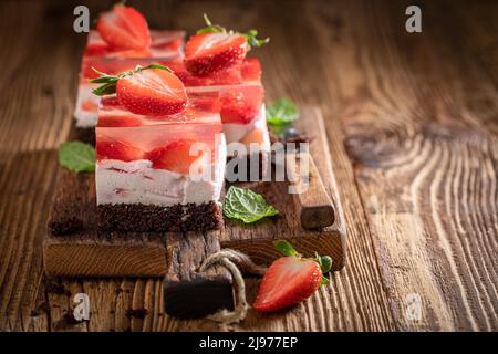 Köstlicher Erdbeer-Gelee-Kuchen mit fruchtiger Schicht, umgeben von Gelee. Gelatinekuchen mit Früchten. Stockfoto