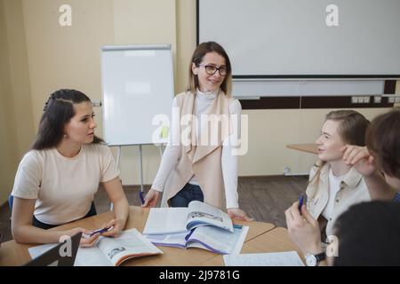 Glückliche, reife Lehrerin, die gerne mit Schülern arbeitet und freudig lächelt Stockfoto