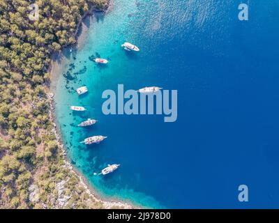 Luftaufnahmen von Drohnen von Tagesbooten und privaten Yachten, die in der Cennet Bay im Dorf Selimiye im Bezirk Marmaris der Stadt Muğla, TU, vor Anker liegen Stockfoto