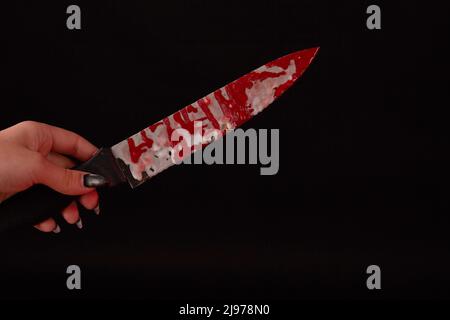 Nahaufnahme weibliche Hand hält ein Messer mit Blut befleckt. Isoliert auf schwarzem Hintergrund. Stockfoto