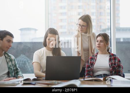 Reife Lehrerin hilft ihren Schülern während des Seminars Stockfoto