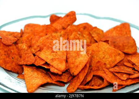 Ein Stapel aromatisierter Tortilla-Chips aus Mais-Tortillas, die in Dreiecke geschnitten und dann gebraten oder gebacken wurden, serviert in einer ovalen Servierplatte, die auf weißem Ba isoliert ist Stockfoto