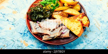 Stücke von gesalzenem Hering mit gebackenen Kartoffeln und Toast. Stockfoto