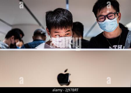 Wuhan, China. 21.. Mai 2022. Chinesische Kunden mit Masken testen bei der offiziellen Eröffnung des neuen Apple Stores auf der Wuhan International Plaza, Wuhan, einen iMac. Apple eröffnete seinen ersten Flagship-Store in Wuhan, ebenfalls den 54. Flagship-Store im Großraum China. Kredit: SOPA Images Limited/Alamy Live Nachrichten Stockfoto