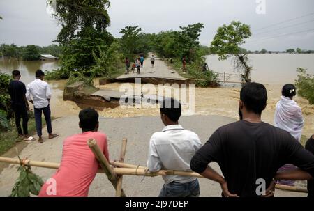 Assam, Indien. 20.. Mai 2022. Dorfbewohner, die am 20. Mai 2022 in Nagaon, Assam, Indien, in der Nähe einer beschädigten Straße standen, nachdem sie starke Regenfälle überschwemmt hatten. Mindestens 10 Menschen sind bei Überschwemmungen und Erdrutschen aufgrund von Regenfällen vor dem Monsun in Assam ums Leben gekommen. Kredit: David Talukdar/Alamy Live Nachrichten Gutschrift: David Talukdar/Alamy Live Nachrichten Stockfoto