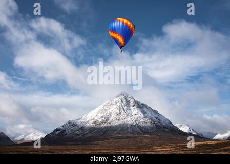 Digitales Composite-Bild von Heißluftballons, die über eine atemberaubende, ikonische Landschaft fliegen Winterbild des Berges Stob Dearg Buachaille Etive Mor in Schottland Stockfoto