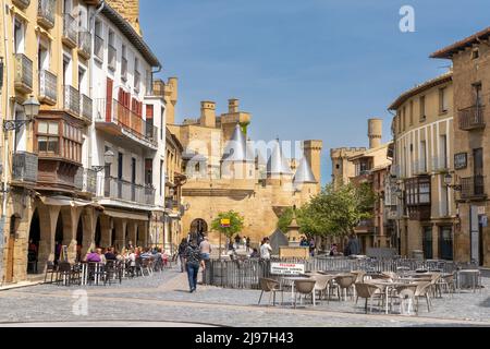 Olite, Spanien - 30. April 2022: Touristen genießen einen Besuch im historischen Olite an einem schönen Sommertag mit dem Palacio Real Schloss im Hintergrund Stockfoto