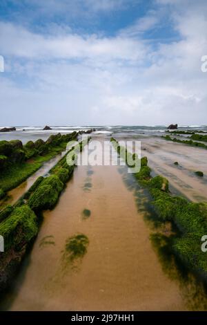 Eine lange Sicht auf die Felsformationen von Flysch bei Ebbe am Strand von Barrika in der Nähe von Bilbao Stockfoto