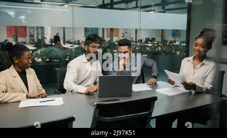 Afrikanische Teamleiterin erklärt Unternehmensentwicklungsstrategie mit Vertragsdokument verschiedene Kollegen in Büromeeting diskutieren Corporate Stockfoto