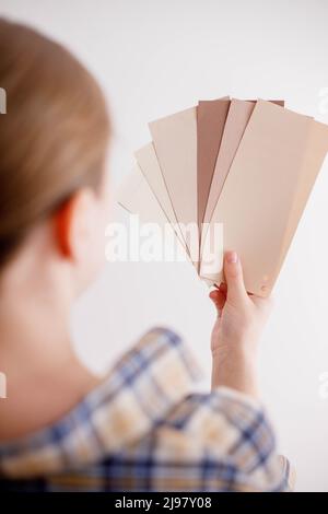 Die junge Frau hält Farbproben für die Wand in der Hand Stockfoto