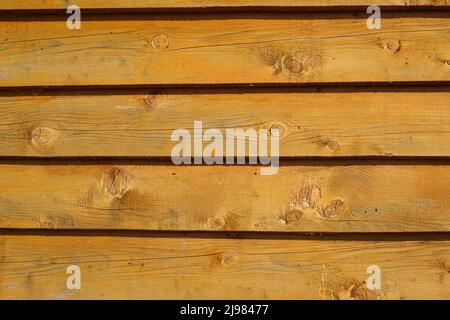 Dekorative Scheibe aus orangefarbenen Plankenmustern auf Holzwandstruktur für den Hintergrund. Stockfoto