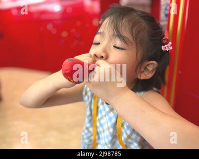 Nettes kleines Mädchen versucht, einen Ballon aufzublasen Stockfoto