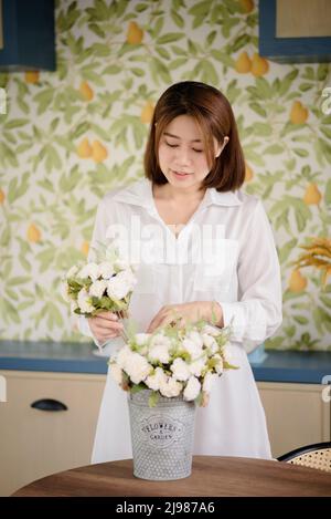 Eine asiatische Frau arrangiert Blumen. Stockfoto