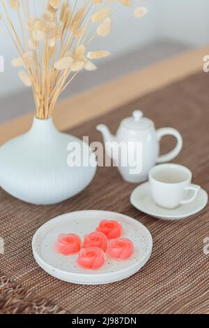 Desserts mit rosa Gelee und einem Set Tee auf dem Tisch. (Selektiver Fokus) Stockfoto