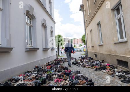 Ostritz, Deutschland. 21.. Mai 2022. Beim Ostritzer Friedensfest läuft ein Mann an vielen Schuhen vorbei. Die Schuhe stehen dort und repräsentieren Menschen, die ihr Leben auf See verloren haben. Das Friendensfest ist seit Jahren fester Bestandteil der Gemeinschaft, um sich gegen rechtsorientierte Ereignisse in der Stadt zu wehren. Quelle: Daniel Schäfer/dpa/Alamy Live News Stockfoto