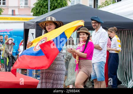 Ostritz, Deutschland. 21.. Mai 2022. Eine Frau tanzt mit einem Hut auf dem Kopf und hält die Flagge Ecuadors an der Modenschau, die das Thema Demokratie, Kosmopolitismus und Toleranz hat. Das Friedensfestival ist seit Jahren ein integraler Bestandteil der Gemeinschaft, um sich gegen rechtsorientierte Veranstaltungen in der Stadt zu wehren. Quelle: Daniel Schäfer/dpa/Alamy Live News Stockfoto