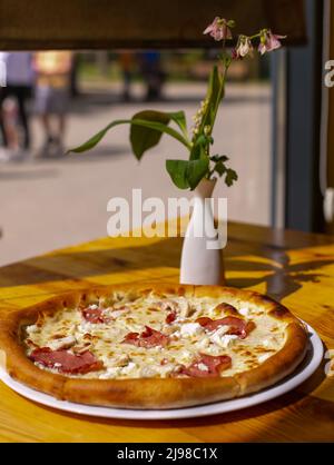 Pizza mit Sauce, Huhn, Käse auf dem Teller auf Holztisch serviert. Stockfoto