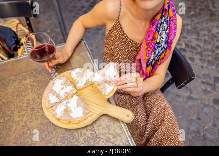 Frau, die im Freien im italienischen Restaurant Pizza isst Stockfoto