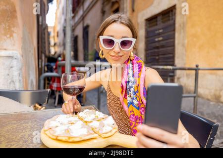 Frau, die im Freien im italienischen Restaurant Pizza isst Stockfoto