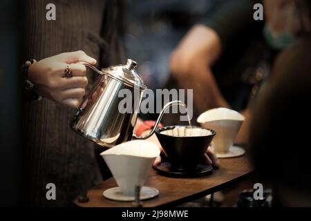 Barista bereitet den Kaffee mit chemex über die Kaffeemaschine und den Wasserkocher zu. Mann, der Kaffee macht. Alternative Möglichkeiten zum Brühen von Kaffee. Café-Bar Stockfoto