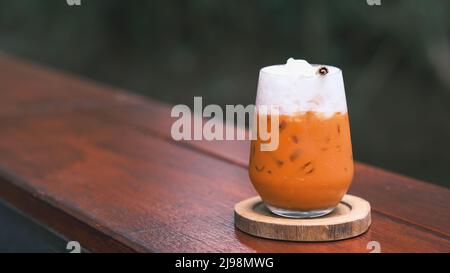 Thailändischer Milchtee, Milcheistee, Cheddar ist ein traditionelles thailändisches Getränk, das seit langem beliebt ist, frisches und süßes Dessert auf einer hölzernen Untertasse, Vintage Woode Stockfoto