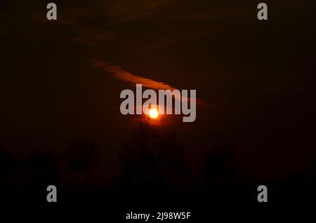 Sonnenuntergang hinter einem dunklen Himmel, wie eine Augenbraue. Stockfoto